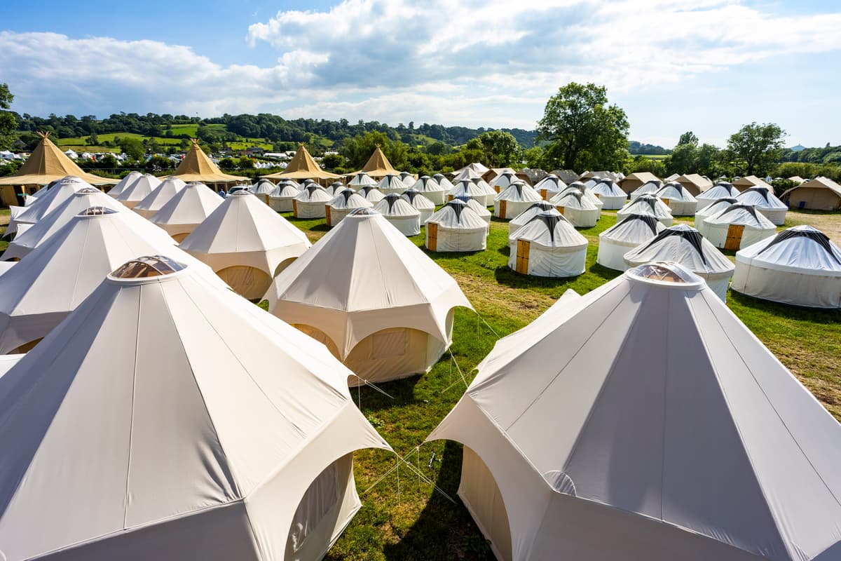 Photograph of bell tents and yurts across a sunny field