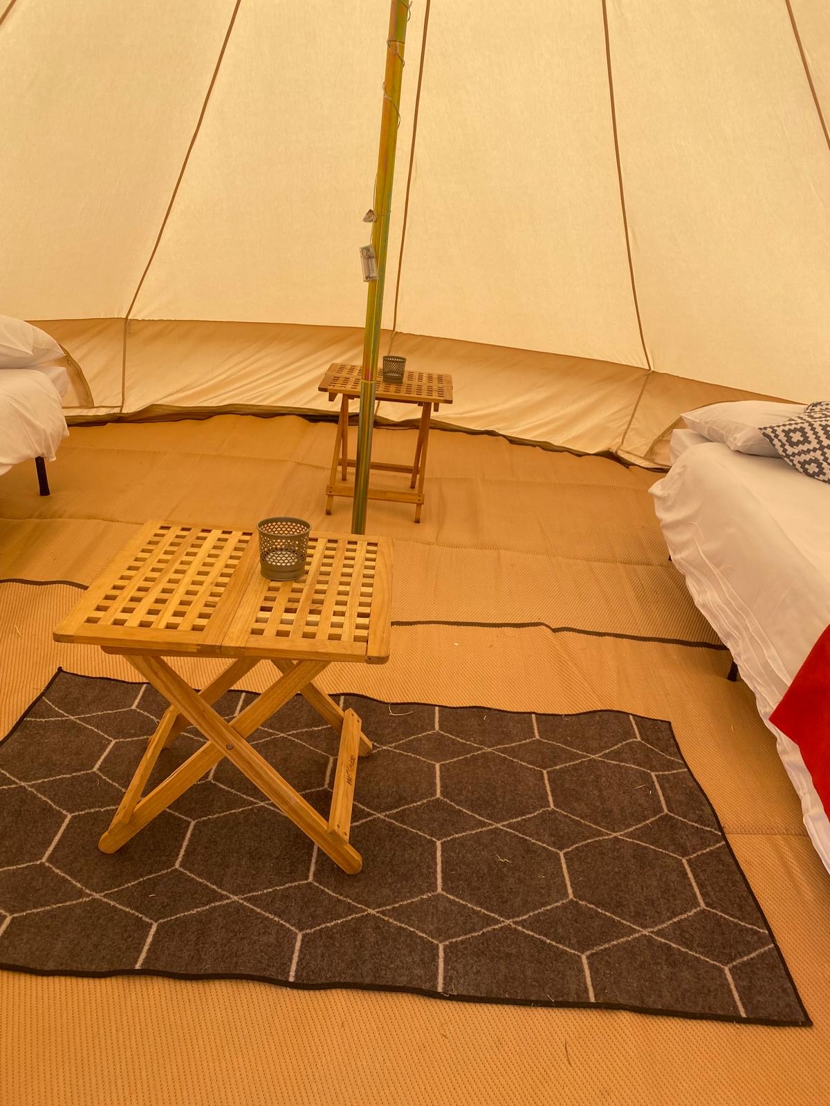 Real bell tent interior with beds, rugs and wooden tables