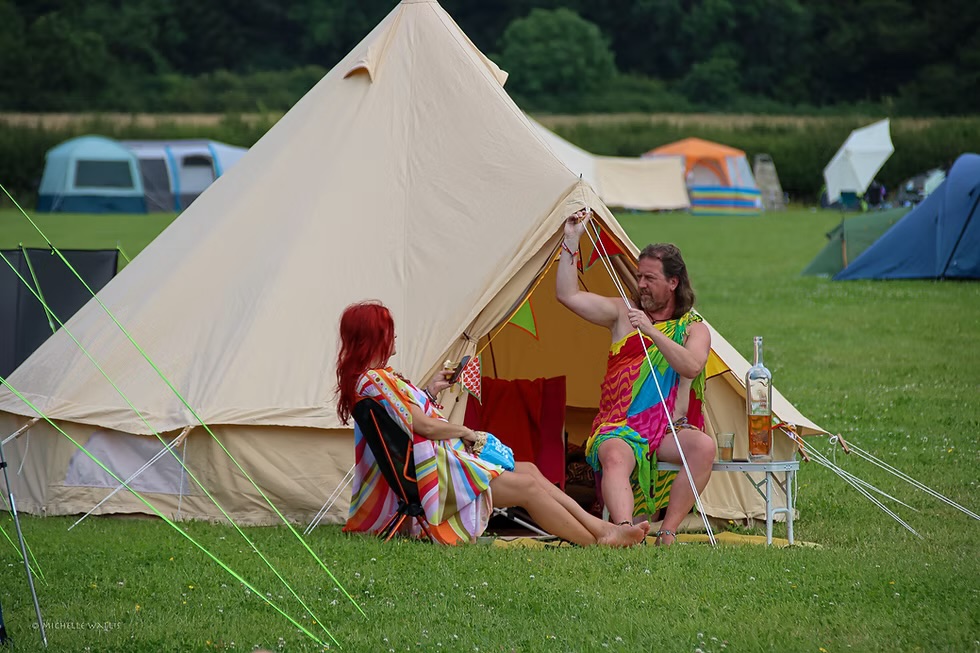 Two festival campers relaxing outside a canvas tent