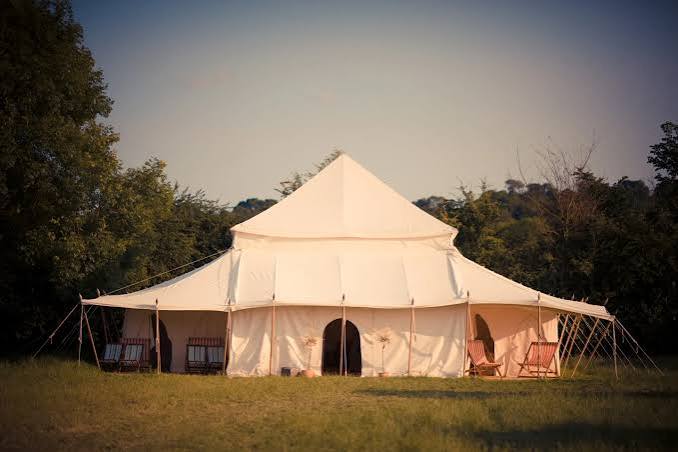 Large canvas pavilion with chairs on grass